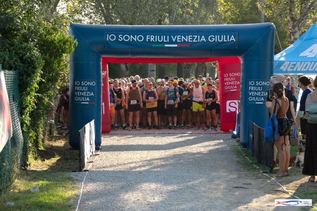 La partenza della Sardon Run: runner schierati sotto l'arco IO SONO Friuli Venezia Giulia