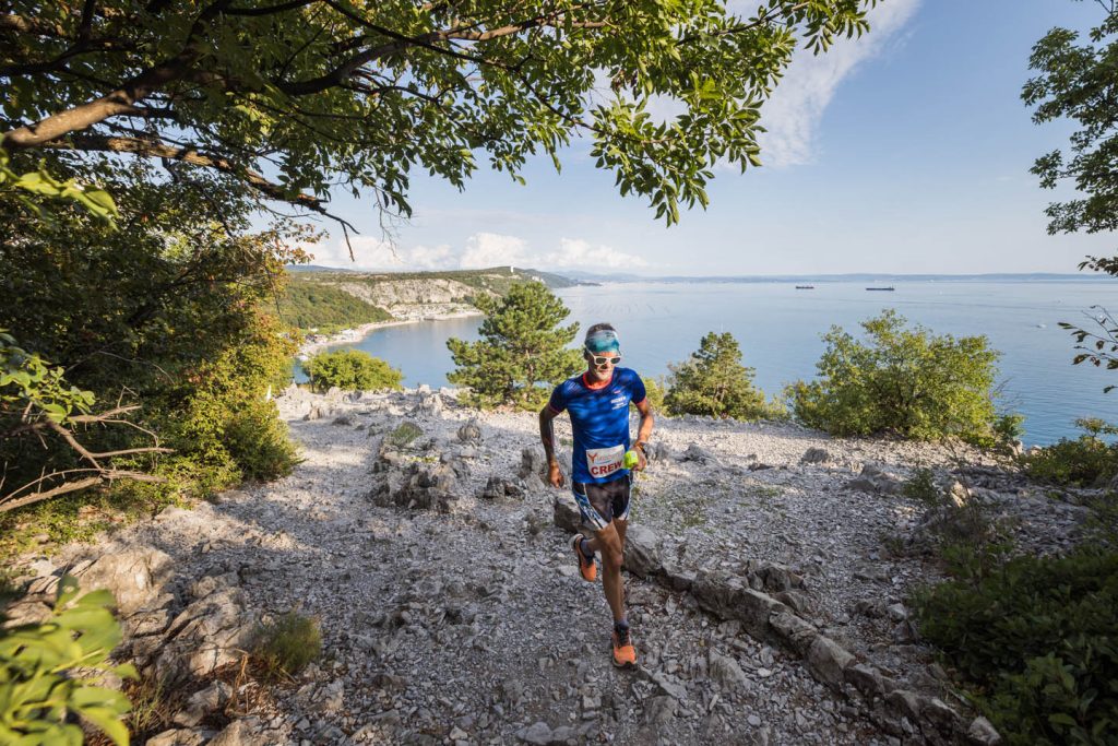 Trail runner sul ciglione carsico sopra la baia, con il mare del Golfo di Trieste alle spalle — Sardon Run