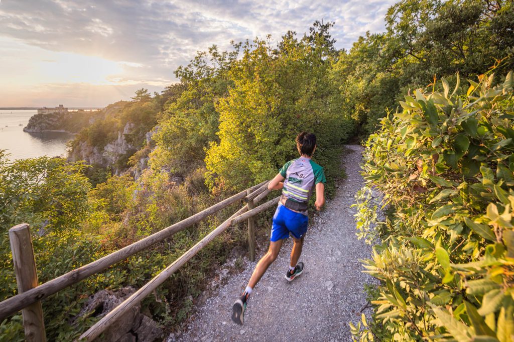 Runner al tramonto sul sentiero panoramico a picco sul mare, lungo il percorso della Sardon Run