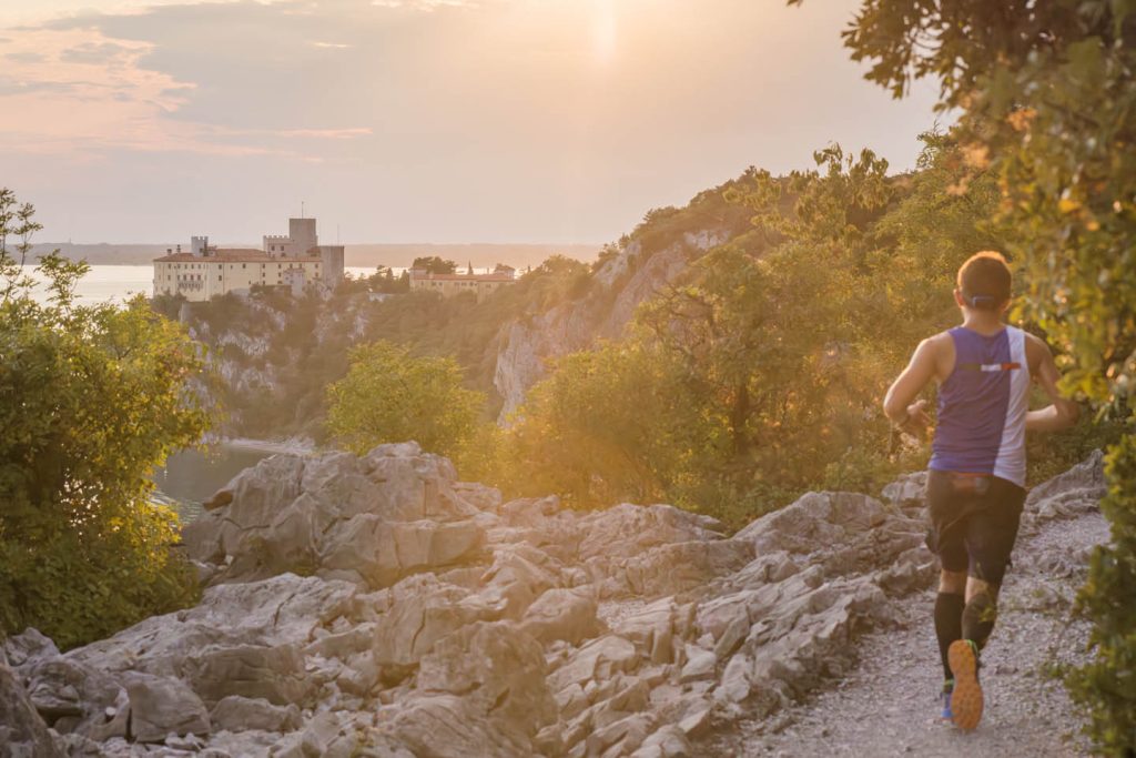 Discesa sulla pietraia carsica verso il Castello di Duino nella luce dorata del tramonto — Sardon Run