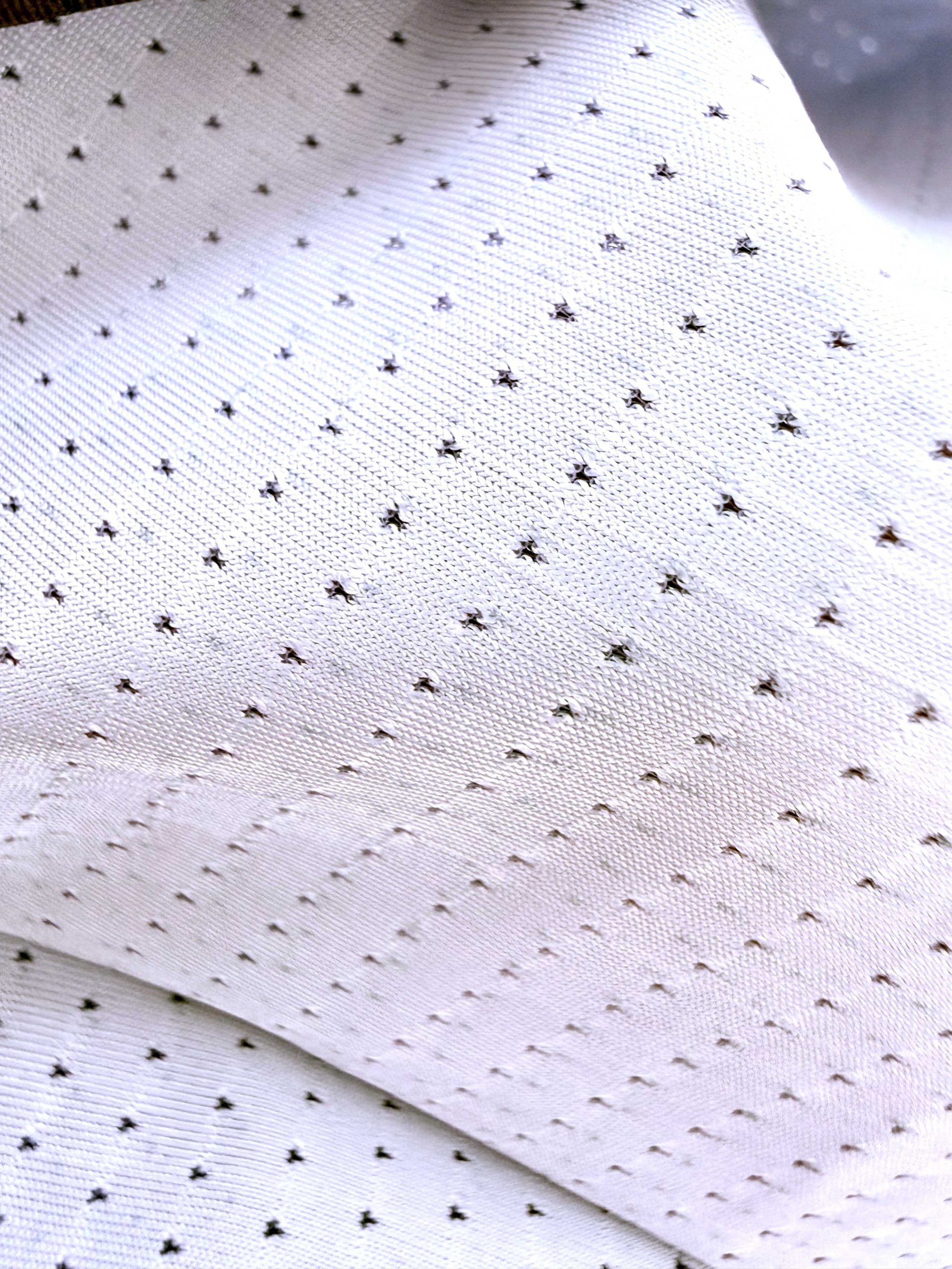 Dettaglio micro-perforazione tessuto tecnico Sardon Run — close up