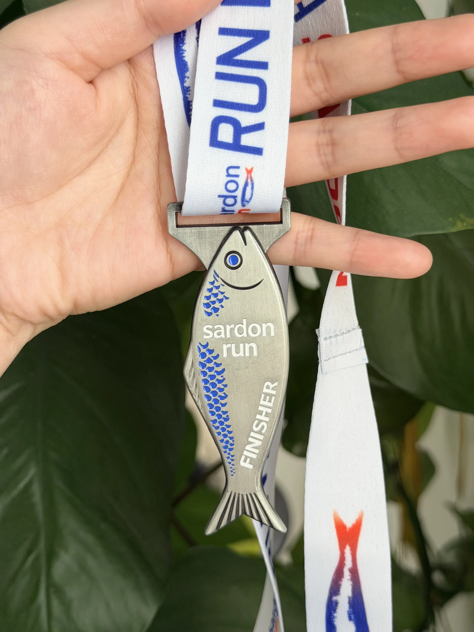 Medaglia finisher Sardon Run 2026 — forma sardina in metallo con nastro bianco